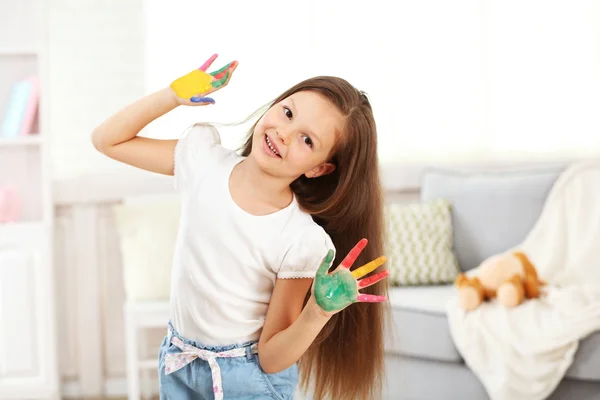 Menina com as mãos na pintura, em casa interior fundo — Fotografia de Stock