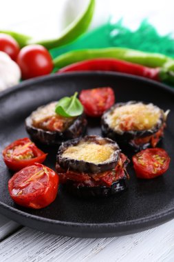 Patlıcan domates ve peynirle ahşap masa, closeup üzerinde siyah tavada