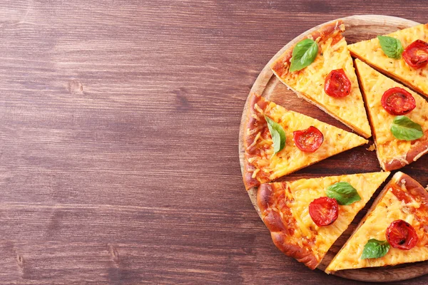 Pizza z bazylią i pomidorkami na stole z bliska — Zdjęcie stockowe