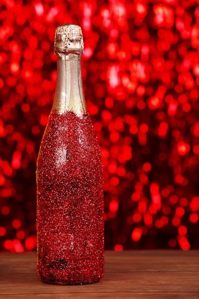 Dekorierte Champagnerflasche auf hellem funkelnden unscharfen Hintergrund — Stockfoto