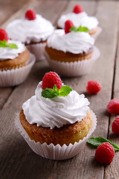 Deliciosos cupcakes con bayas y menta fresca en la mesa de madera de cerca — Foto de Stock