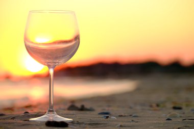 Wineglass on seashore suring sunset clipart