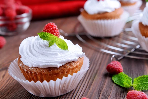 Delicious cupcakes with berries and fresh mint on wooden table close up — Stock Photo, Image