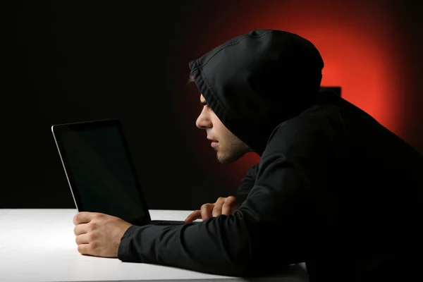 Hacker met computer en laptop op kleurrijke donkere achtergrond — Stockfoto