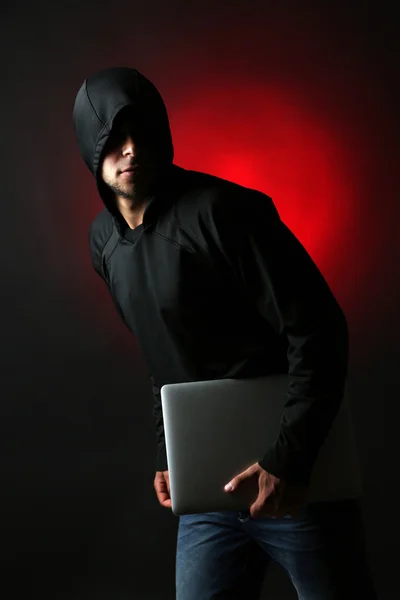 Hacker com computador e laptop sobre fundo escuro colorido — Fotografia de Stock