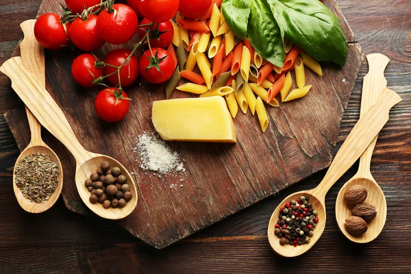 Pasta penne con pomodori, formaggio, spezie e basilico su fondo rustico in legno — Foto Stock