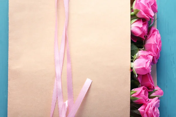 Mooie rozen in envelop op houten achtergrond — Stockfoto