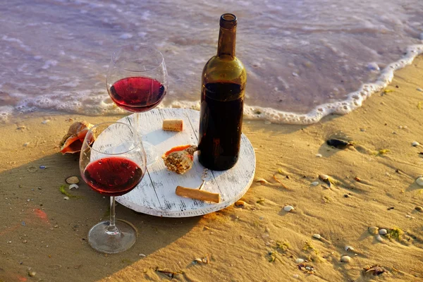 Botella de vino y copas sobre arena — Foto de Stock