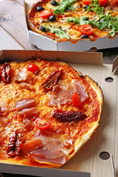 Pizza in box on wooden table closeup