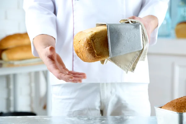 Пекарь проверяет свежеиспеченный хлеб — стоковое фото