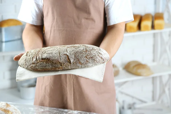 Пекарь держит свежеиспеченный хлеб — стоковое фото