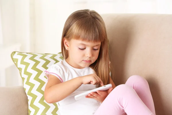 Dziewczyna z inteligentny telefon siedzi na kanapie — Zdjęcie stockowe