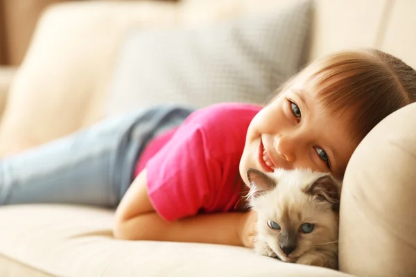 Chica con gatito en sofá en casa — Foto de Stock