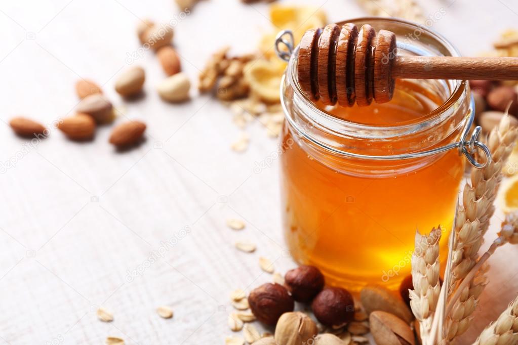 Honey in glass jar and nuts.