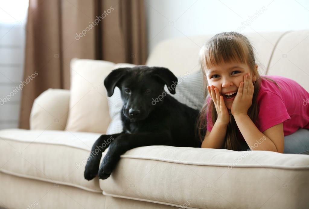 girl with puppy on sofa at home