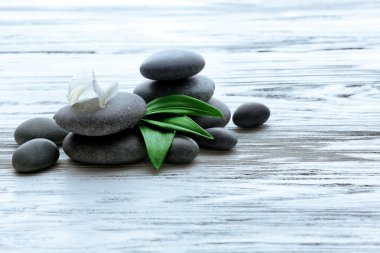 Ahşap arka plan üzerinde Spa taşlarla çiçek ve yeşil yaprakları