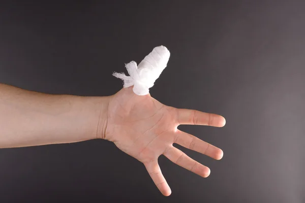 Injured bandaged finger on dark background — Stock Photo, Image
