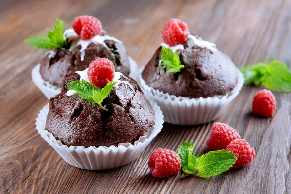 Leckere Schokoladen-Cupcakes mit Beeren und frischer Minze auf Holztisch aus nächster Nähe — Stockfoto