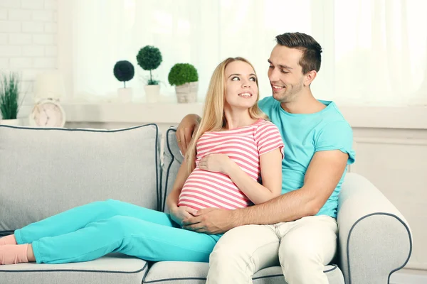 Pregnant woman with husband on sofa — Stock Photo, Image
