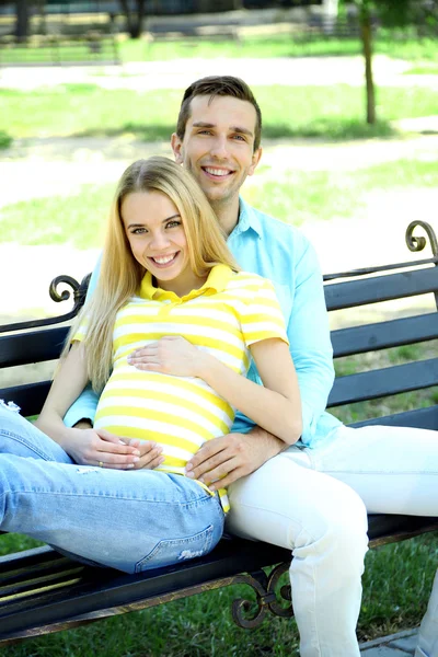 Pregnant woman with husband sitting on bench — Stock Photo, Image