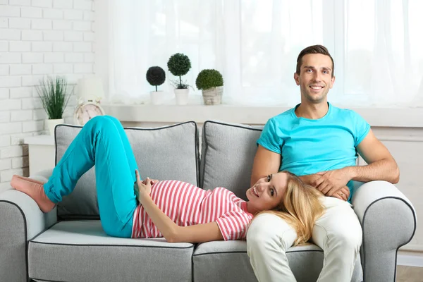 Pregnant woman with husband on sofa — Stock Photo, Image