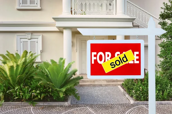 Real estate sign in front of new house for sale — Stock Photo, Image