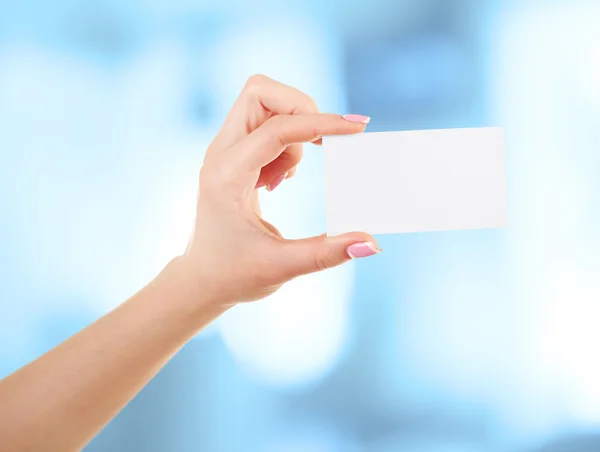 Mano sosteniendo tarjeta en blanco sobre fondo abstracto — Foto de Stock