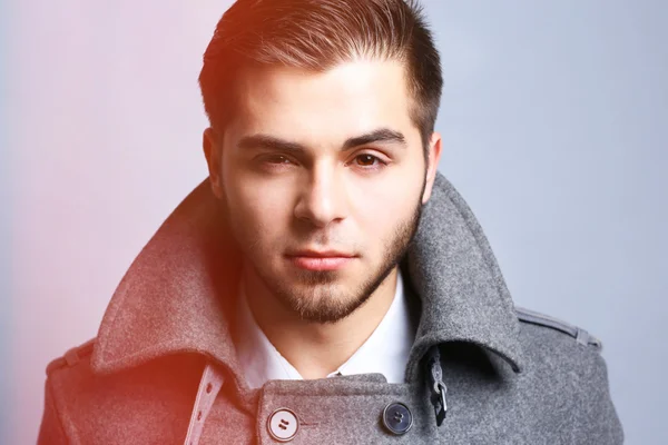 Fiatal férfi kabát szürke háttér — Stock Fotó