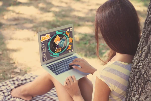 Beautiful young girl with laptop in park — Stock Photo, Image