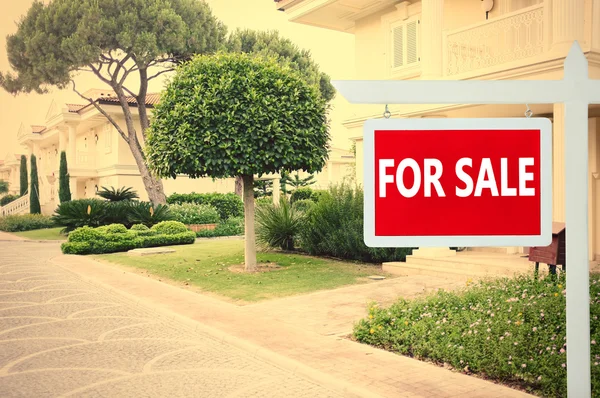 Real estate sign in front of new house for sale — Stock Photo, Image