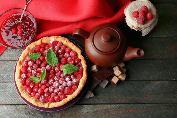 Tart with fresh raspberries and teapot, on wooden background — Stock Photo, Image