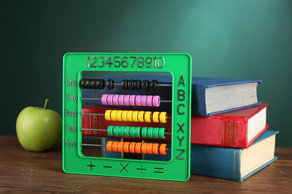 Kleurrijke abacus met stapel boek zand groene appel op Bureau op groene schoolbord achtergrond — Stockfoto