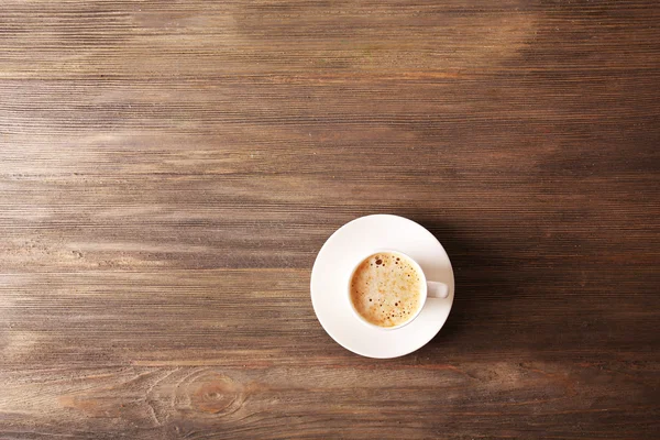 Cup of coffee with foam on wooden table, top view — Stock Photo, Image