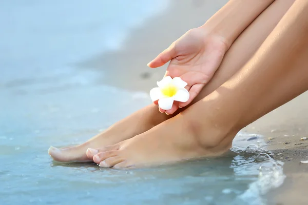 砂浜に花と女性の足 — ストック写真