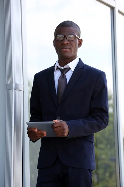 Hombre de negocios afroamericano guapo con tableta digital cerca del centro de negocios —  Fotos de Stock