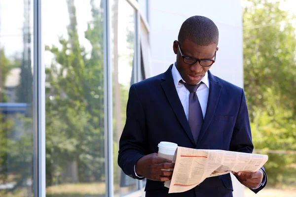 Knappe Afro-Amerikaanse zakenman met krant in de buurt van business-centrum — Stockfoto