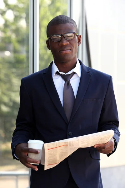 Handsome African American businessman with newspaper near business centre — Stock Photo, Image