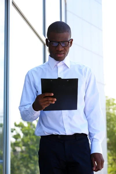 Beau homme d'affaires afro-américain avec presse-papiers près du centre d'affaires — Photo