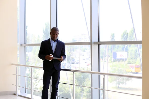 Handsome African American businessman with tablet and cup of coffee in office — Stock Photo, Image