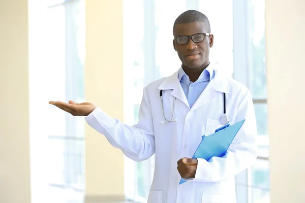 Guapo médico afroamericano sujetando portapapeles en el hospital — Foto de Stock