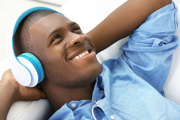 Hombre afroamericano guapo con auriculares acostados en el sofá de cerca —  Fotos de Stock