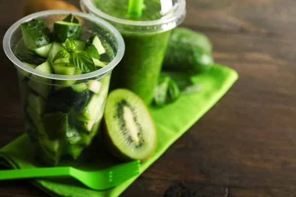 Ensalada de verduras y frutas verdes y bebida fresca saludable en tazas de plástico sobre fondo de madera. Colorido concepto de dieta —  Fotos de Stock