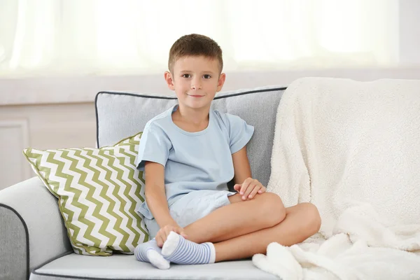 Niño sentado en el sofá, en el fondo interior de casa — Foto de Stock