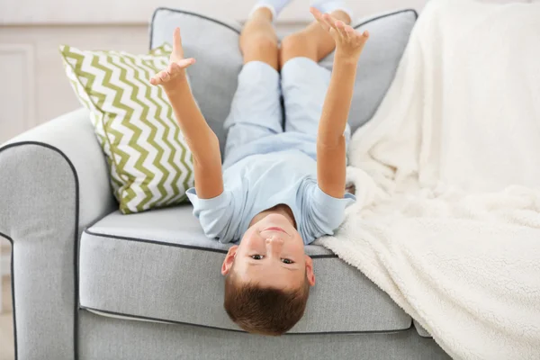 Niño sentado en el sofá, en el fondo interior de casa — Foto de Stock
