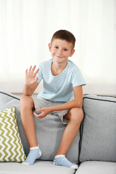 小男孩坐在沙发上，在家庭内部的背景上 — 图库照片