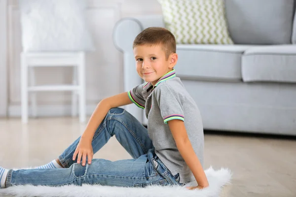 Petit garçon assis sur le tapis, sur le fond intérieur de la maison — Photo