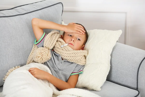 Niño enfermo con frío sentado en el sofá — Foto de Stock