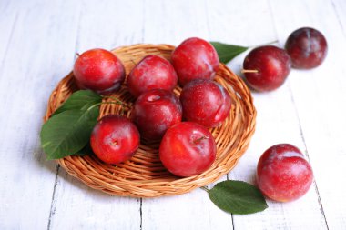 Hasır tepsi ahşap arka plan üzerinde olgun Erik