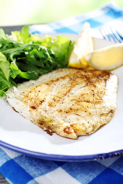 Plato de filete de pescado con lechuga y limón en la mesa de cerca — Foto de Stock