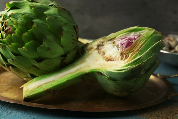 Artichokes on tray, on color wooden background — Stock Photo, Image